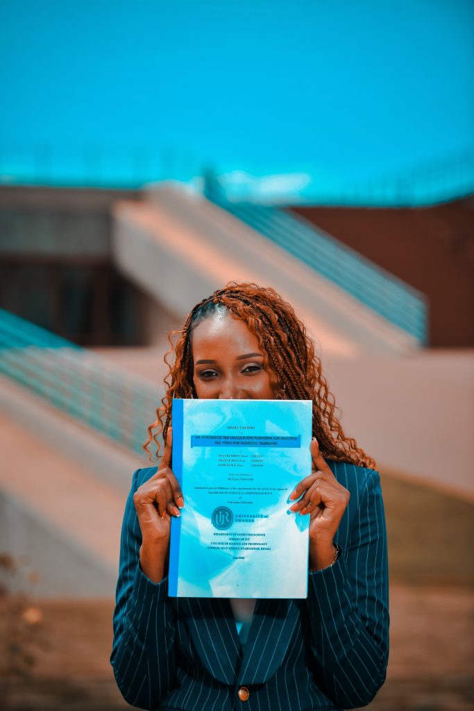 A joyful adult woman holding her thesis document outdoors, symbolizing academic achievement.